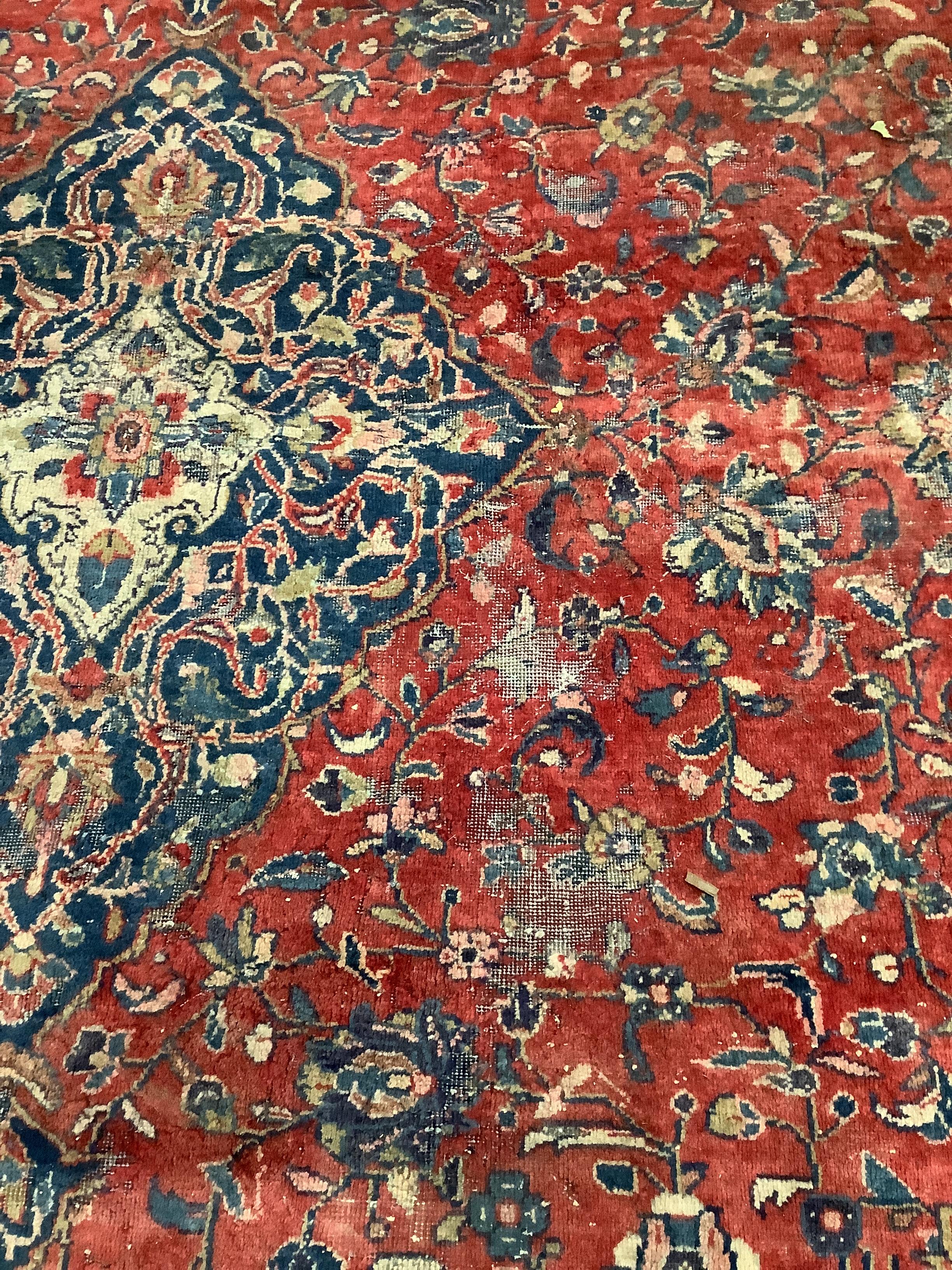 A Persian brick red ground carpet, 382 x 300cm (severely worn in patches)
